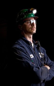 A worker with a uniform and safety glasses and a hard hat.