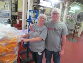 Two employees in MarionMade! shirts with hair nets work inside the factor. 