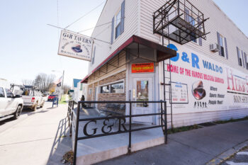 The exterior of a 2-story building with siding and a G&R Tavern sign above the door.