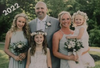 The family poses together while wearing formal clothes and carrying flowers.