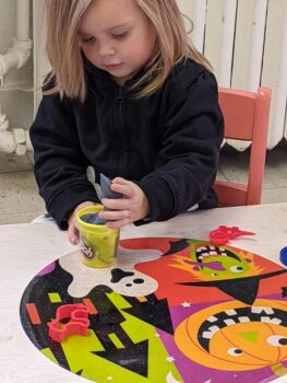 A young girl with shoulder-length blonde hair plays with Play Doh.