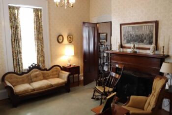 An interior room with antique furniture and light patterned wallpaper.