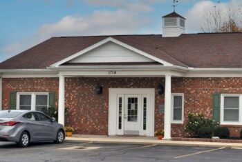 Photo of the office, a brick building with white trim.