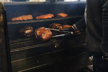 Robert moves the meat in his large commercial smoker. 