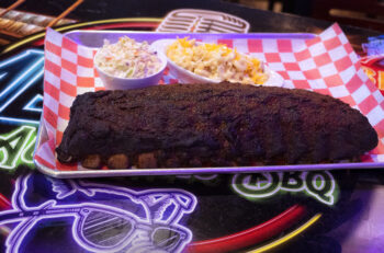 A platter of ribs with a side of coleslaw and mac'n'cheese. 