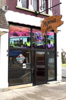 The exterior of the restaurant with a wooden big-shaped sign over the door. 