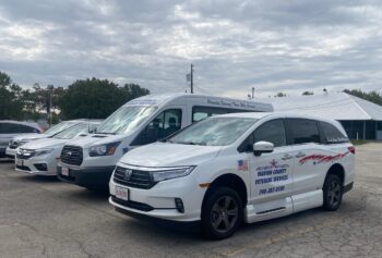 A row of white painted vehicles included a small bus and an SUV. 