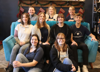 A group of the staff sits on a couch and smiles.