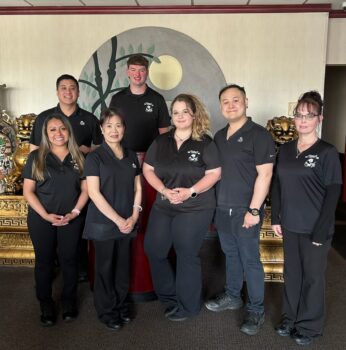 A group of employees stand at the entrance to the House of Hunan in black uniforms. Two golden dragon statues are in the background.