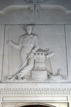 A stone carving insid ethe chappel shows a sailor in uniform who is leaning against a railing. He holds a rope an an anchor leans against the other side. He holds a wooden paddle. 