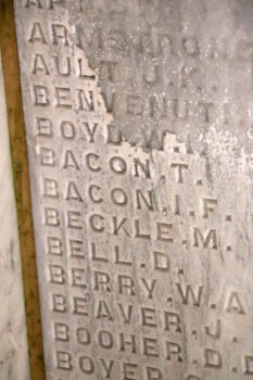 A list of names carved into the stone inside the chapel has water damage, making the names hard to read. 