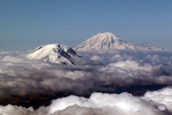 Two snow-covered peaks rise out of the clouds. 