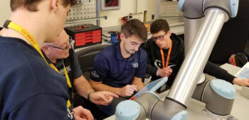 Students work with an instructor on robotic equipment in the RAMTEC lab.