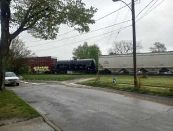 Train cars stopped alongside a road.