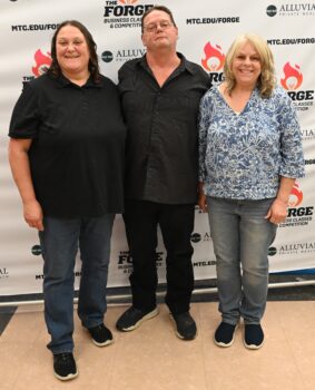 A woman smiles next to two supporters in the Alluvial Private Wealth Forge Competition.