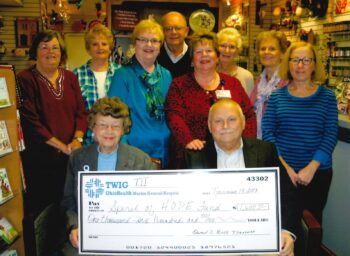 Volunteeers stand around a giant check.