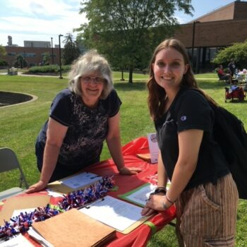 A woman talks to a college student on the Marion Campus. A table has info on registering to vote.