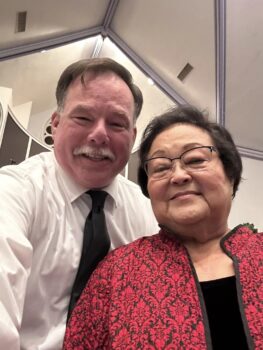 The current and past Civic Chorus presidents pose. Brian is a white man with a gray mustache. Ednita is an Asian woman with short black hair and glasses.