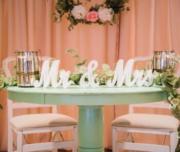 Green tn table with two chairs and a Mr & Nrs wooden sign and other decor. 