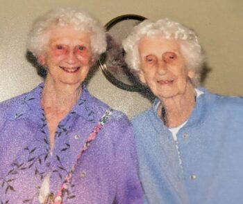 Two smiling white women with short white hair.