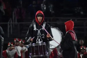 A student marches and drums.