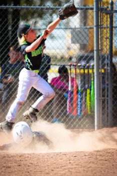 A player in a baseball uniform and glove reaches for a ball.