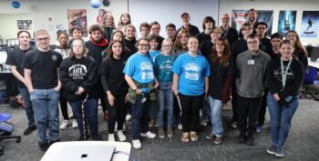A group of teenagers and their instructors smile.