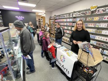 Students smile while showing their comic books to shoppers.