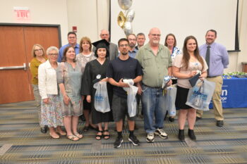 Graduates, instructors and collegleaders smile.