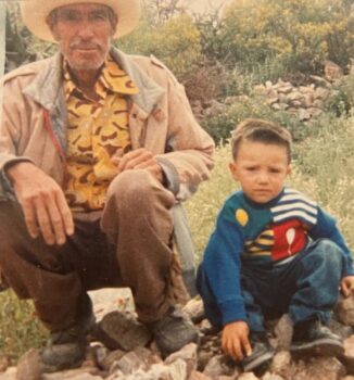 A young boy outside with his grandfather.