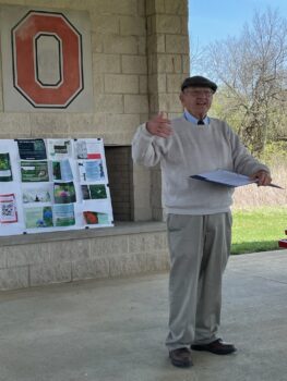 A man gives a talk ainside a stone shelter at the prairie.