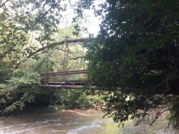 A flat bridge suspended over water with a curved, arched metal top.