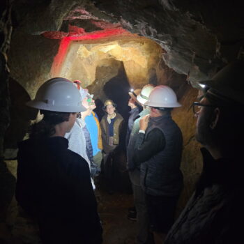The Scouts wear helmets with lights on them in a tunnel.