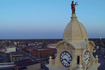 A photo of the Lady Justice statue atop the yellow dome of the clock tower. 