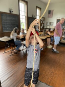 A child pulls a rope to ring the bell.