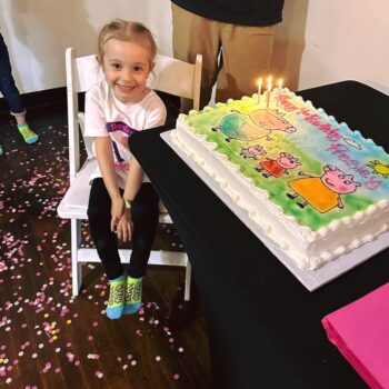 A girl smiles while next to a birthday cake at MaxAiir.