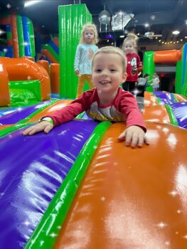 A small child smiles on an inflatable at the MaxAiir inflatapark.