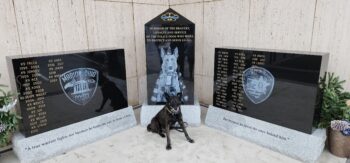 A police dog sits in front of three granite pillars with the names of Marion County K9 officers going back to 1973.